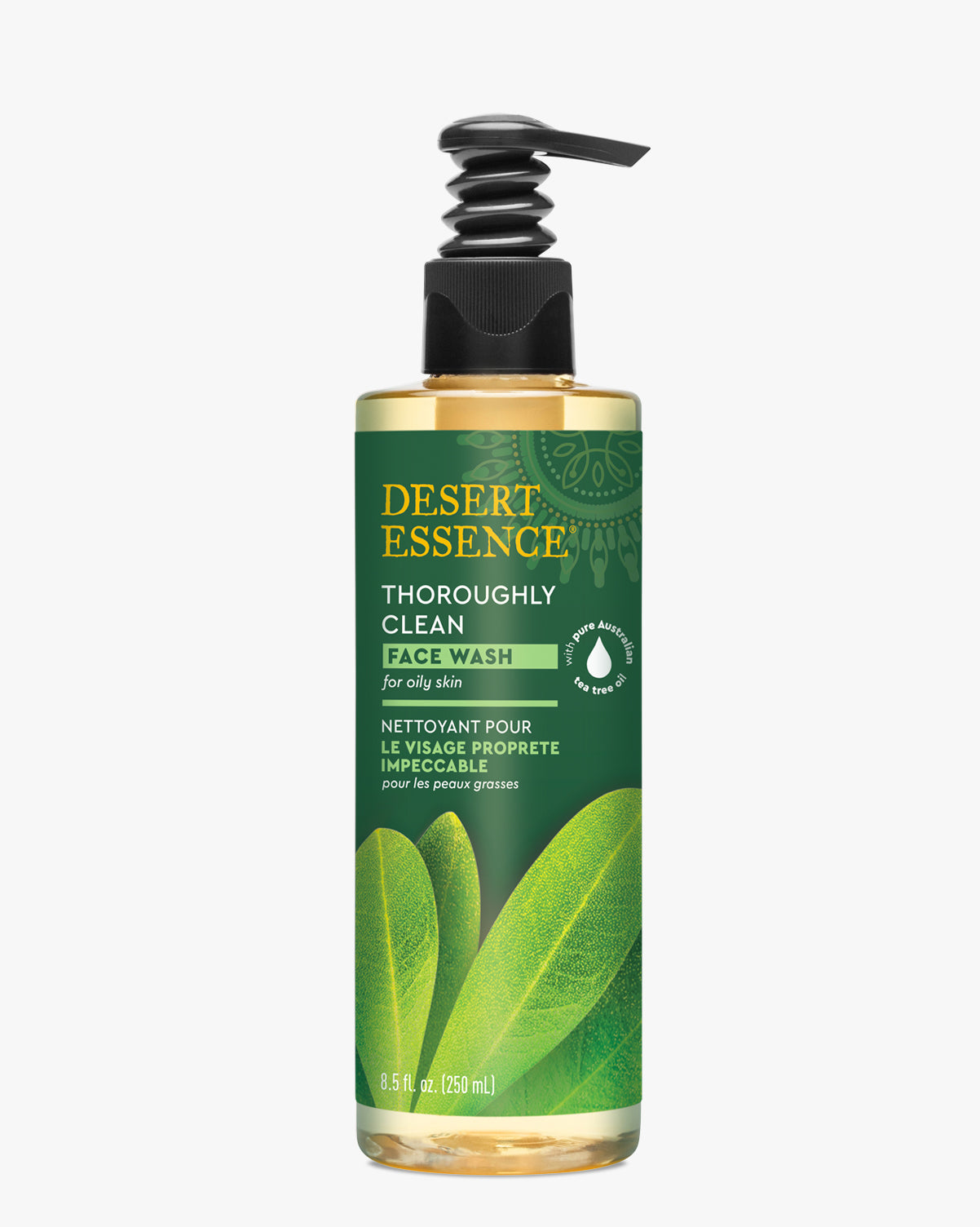 Desert Essence Thoroughly Clean Tea Tree Oil Face Wash bottle with green label and black pump dispenser, featuring translucent golden liquid and decorative leaf imagery against a green background