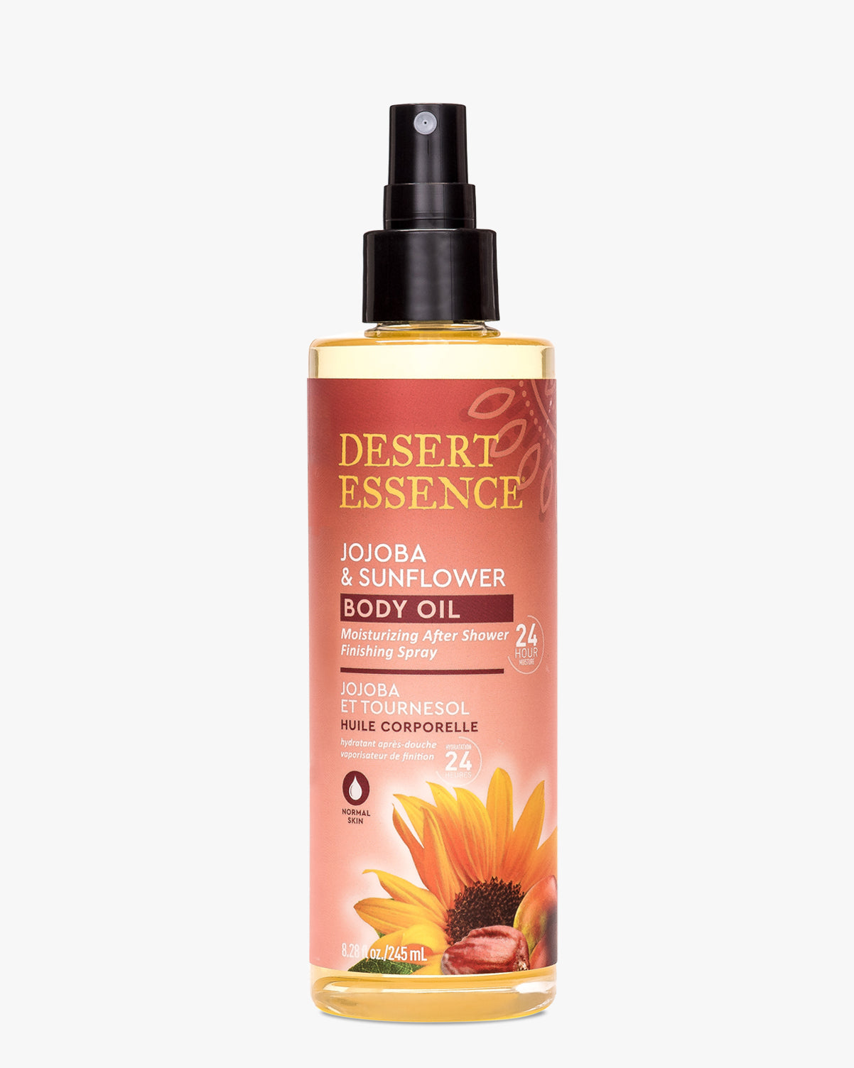 Desert Essence Jojoba & Sunflower Body Oil Spray bottle featuring a clear glass container with black spray nozzle, filled with golden oil. Product label shows vibrant sunflower illustration on coral background with gold text detailing 24-hour moisturizing benefits.