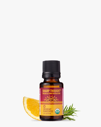 Sharp Thought Organic Essential Oil bottle with purple and orange label displayed alongside fresh orange slice and rosemary sprig, showcasing natural ingredients for focus and concentration blend by Desert Essence