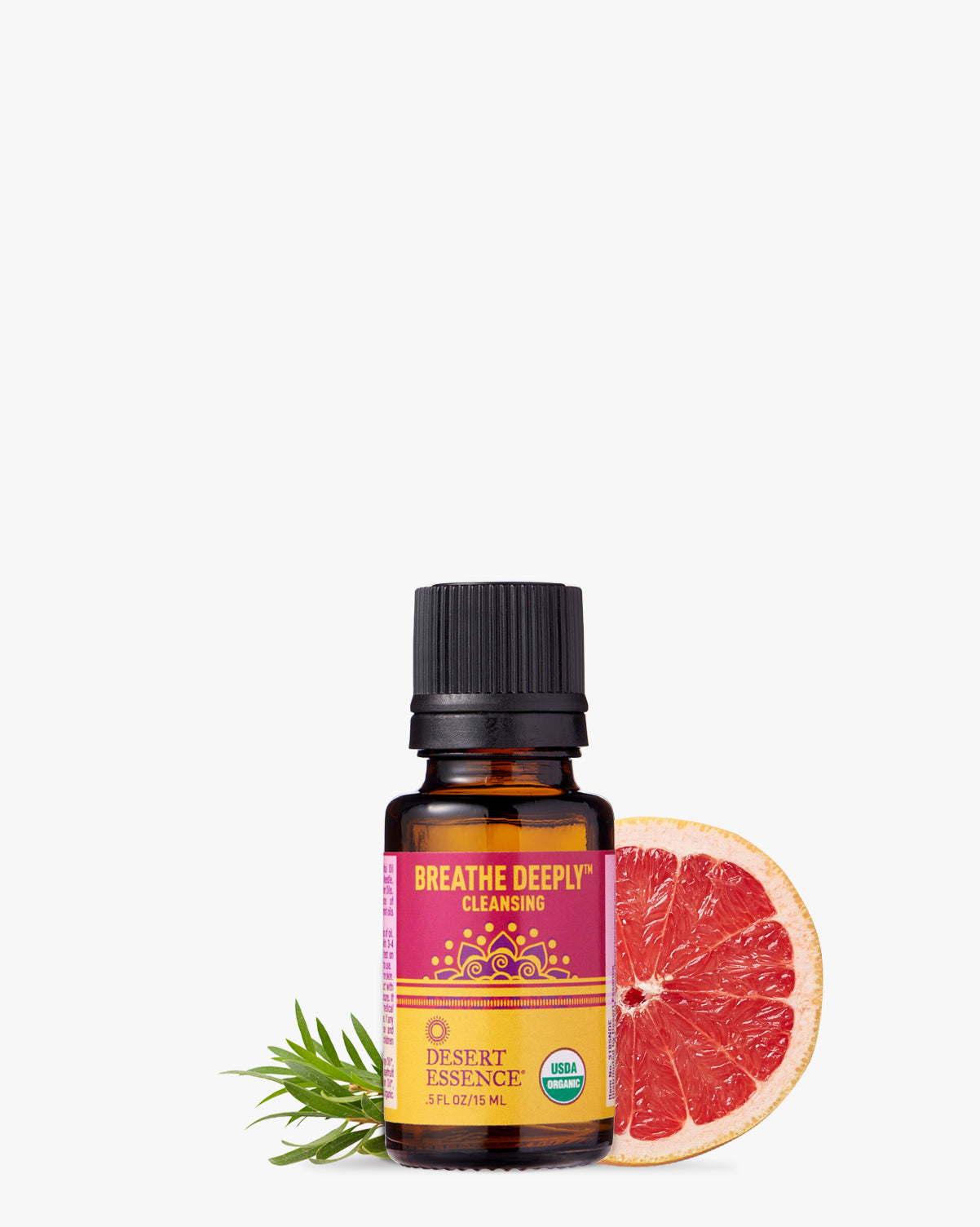 Breathe Deeply Organic Essential Oil bottle displayed with fresh grapefruit slice and pine needles against white background, featuring vibrant pink and yellow label design from Desert Essence brand
