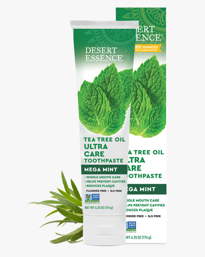 Desert Essence Tea Tree Oil Ultra Care Toothpaste packaging with green leaves on a white background