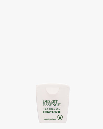Tea Tree Oil Dental Tape by Desert Essence in a compact white dispenser with green text and eco-friendly logo, featuring sustainable beeswax-coated tape infused with natural tea tree oil and mint for effective dental cleaning.