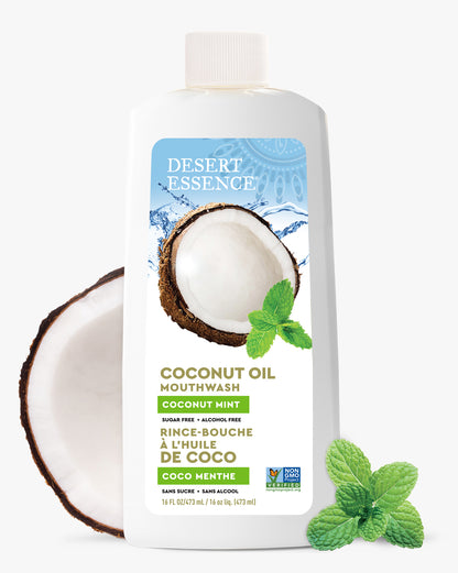 Desert Essence Coconut Oil Mouthwash bottle with a coconut half and mint leaves on a white background