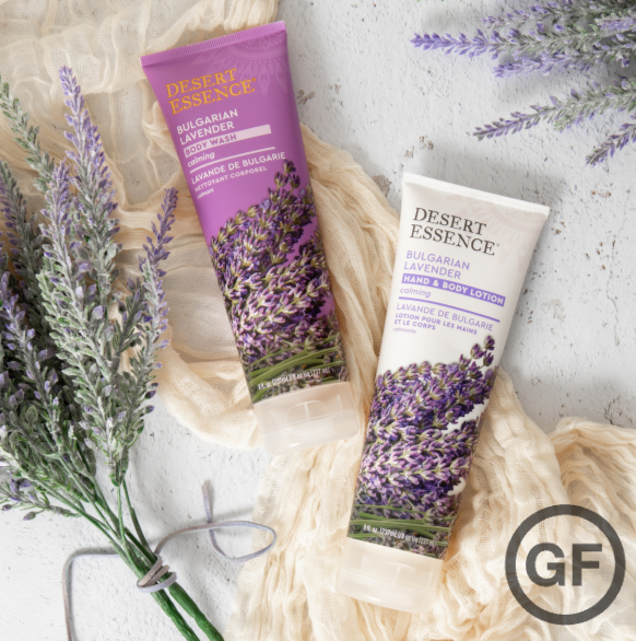 Desert Essence Bulgarian Lavender Hand & Body Lotion tubes with a background of fresh lavender sprigs and a delicate beige fabric, marked with a gluten-free symbol.