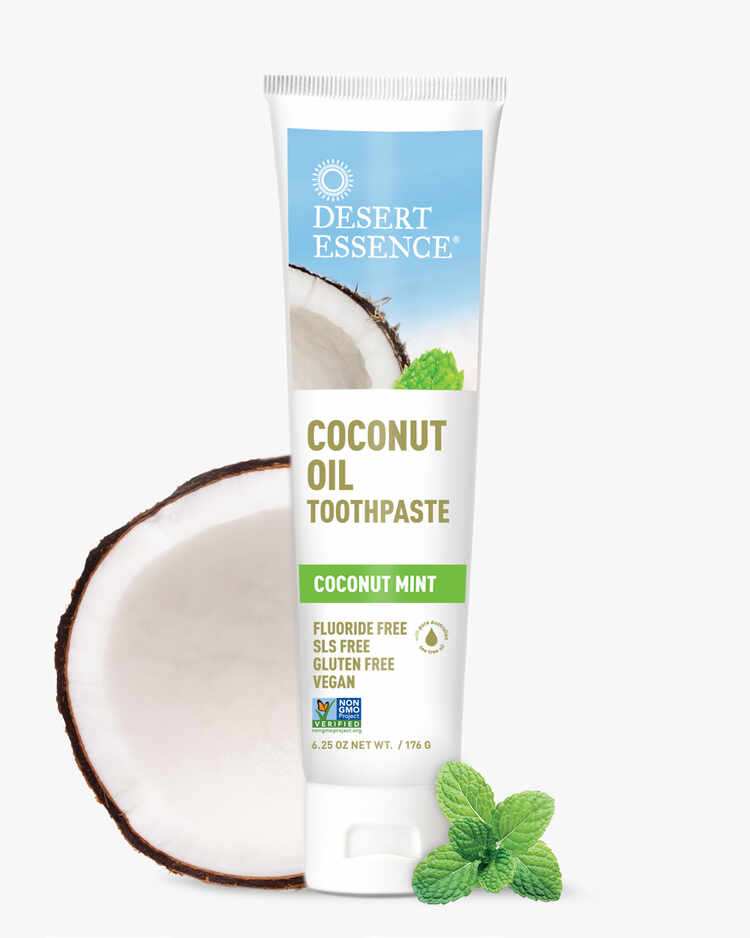 6.25 oz. tube of the Coconut Oil Toothpaste Coconut Mint next to a coconut by Desert Essence.
