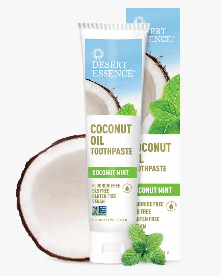 6.25 oz. tube of the Coconut Oil Toothpaste Coconut Mint next to a coconut and packaging by Desert Essence.