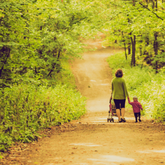 An image of a mother walking her son through a wooded area 